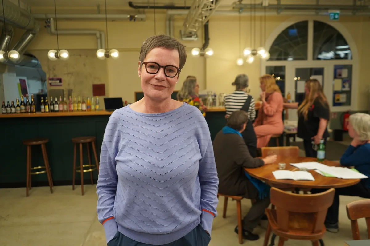 Beatrice Stebler in blaueme Pulli vor der Bar in der Garage.